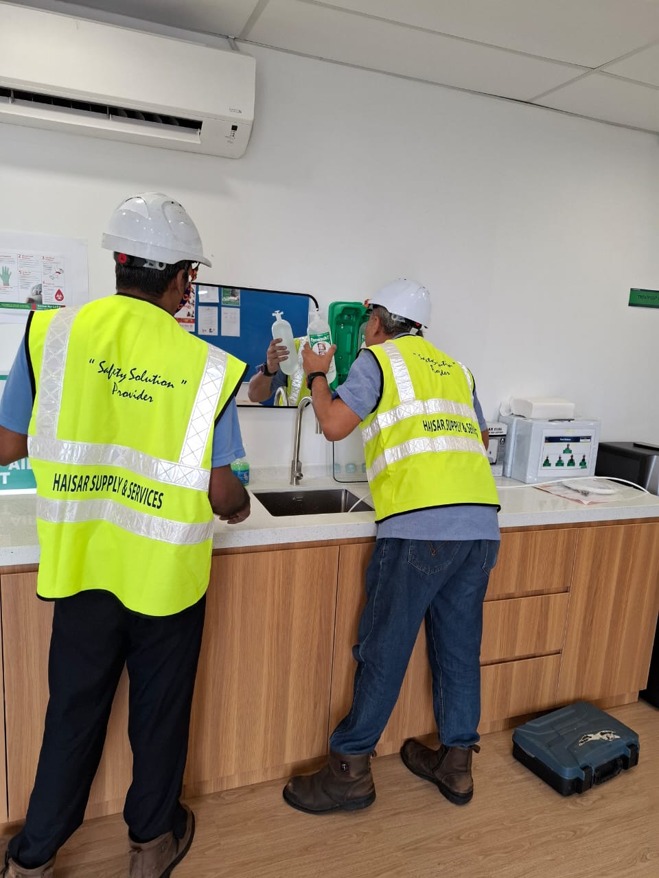 Haisar personnel reviewing emergency eyewash equipment at a workplace