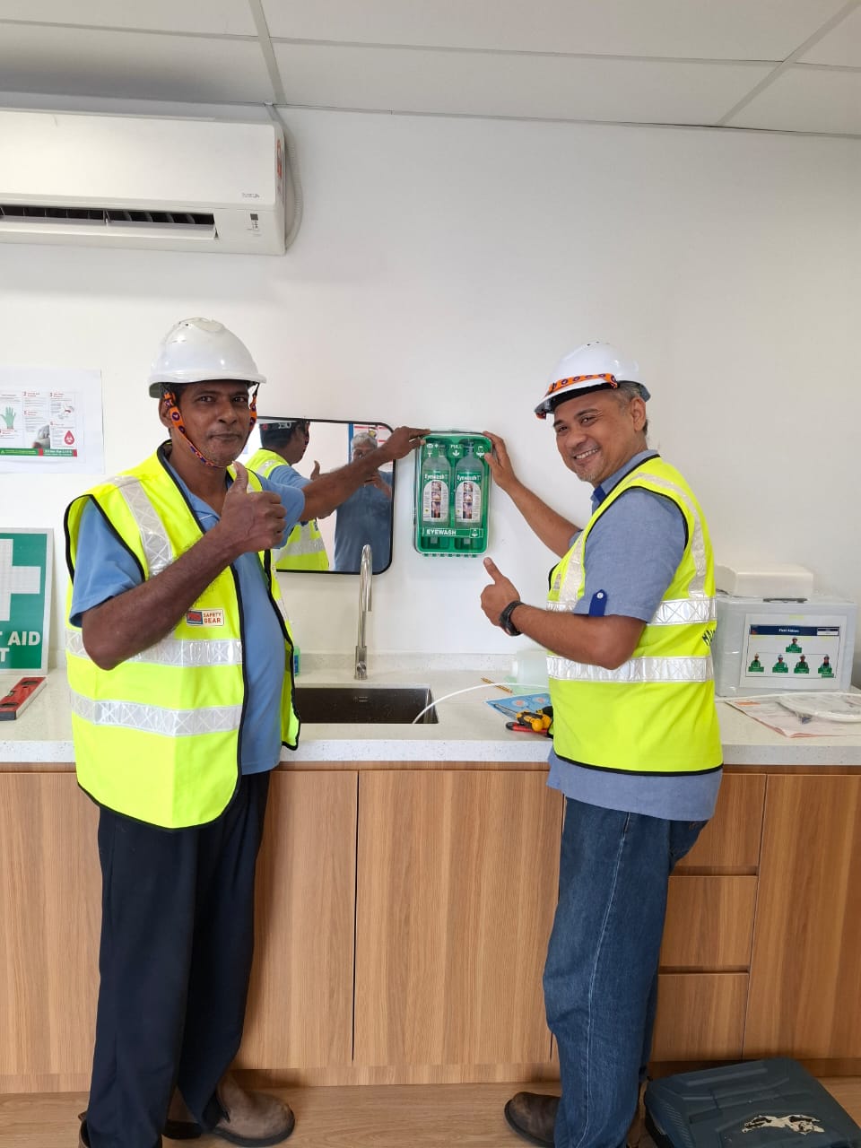 Haisar team and collaborator beside wall-mounted emergency eyewash equipment